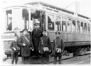 Schwar-weiß Bild einer Straßenbahn um 1912 mit 4 Männern im Vordergrund