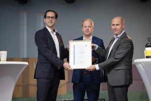 Projektleiter Thomas Brandenburg (M.) übergibt den Stadtwerke-Geschäftsführern Karsten Rogall (r.) und Dr. Maik Piehler (l.) das TÜV-Zertifikat, das dem HKW Leipzig Süd H2-Rediness bescheinigt.